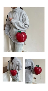 Détail d'un mini sac bandoulière rouge brillant en forme de pomme avec une chaîne dorée