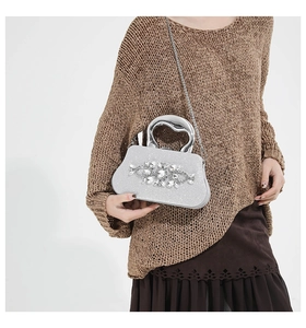 Close-up of sparkling silver glitter evening clutch with crystal flower and metal handle