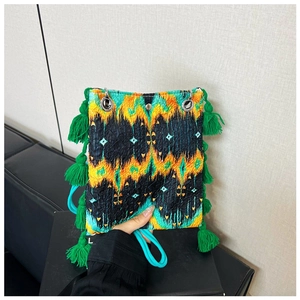 Détails de la texture du sac ethnique avec pompons verts et motif imprimé ikat