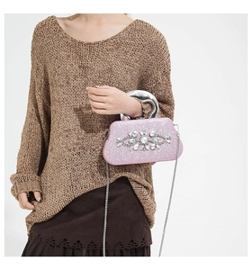 Detailed shot of pink glitter evening clutch featuring large rhinestone floral cluster and metal handle