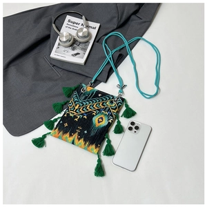 Détail des motifs brodés ethniques et des pompons verts sur le sac cabas noir