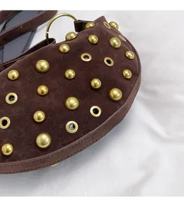 Detail of dark brown suede crescent bag with gold rivets and hollow metal rings