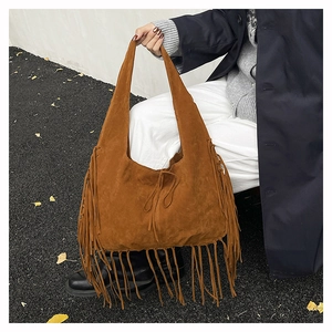 Caramel suede hobo tote bag with long fringes shown on an asphalt autumn street