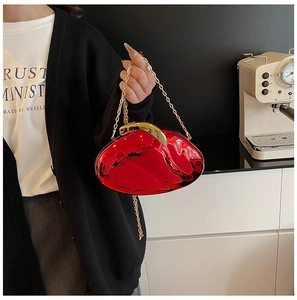 Detail of red mirror heart clutch bag with gold chain strap and luxury metallic finish