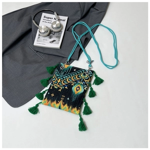 Détail de broderie bohème et glands verts sur un sac à bandoulière ethnique compact