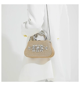 Close-up of golden glitter evening clutch featuring rhinestone floral ornament and metal handle