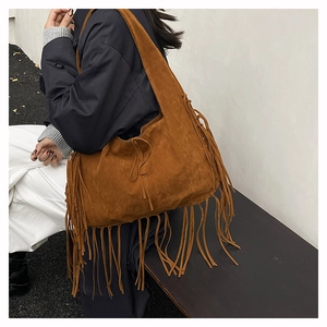 Brown suede bohemian tote bag featuring long fringes styled with casual attire on model
