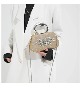 Detail of gold sequin clutch with silver curved metal handle and crystal flower cluster