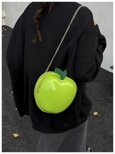 Détail du sac pomme vert vif avec finition brillante et bandoulière dorée