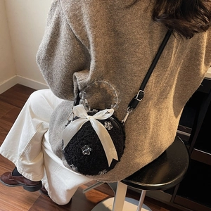 Furry black round crossbody bag with white bow, clear bead handle, and soft plush texture
