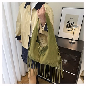 Close-up of green suede tote bag with long bohemian tassels and drawstring closure