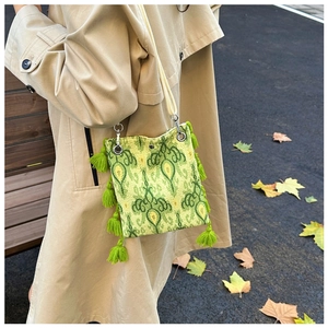 Détail d'un sac bohème au motif jacquard vert avec franges porté par un mannequin extérieur