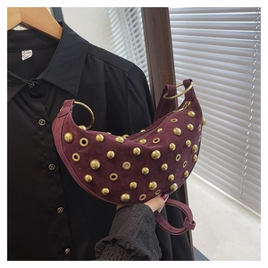 Détail macro du sac en daim bordeaux avec rivets dorés denses et œillets métalliques chic
