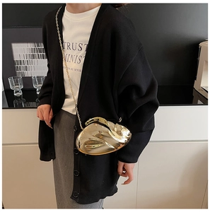 Detail of a luxury gold irregular liquid metal clutch bag with a sleek chain strap