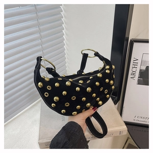 Detail of black crescent suede bag with gold studs, ring handle, and thin shoulder strap
