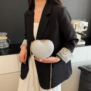 Chic heart-shaped silver sequin handbag with gold chain strap shown in a lifestyle setting