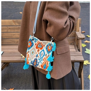 Sac fourre-tout ethnique à motif ikat et pompons bleus sur fond de manteau d'automne