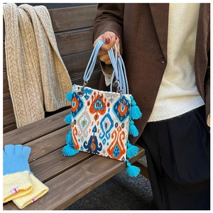 Détail d'un sac ethnique avec motifs ikat, pompons bleus et anses en corde ronde