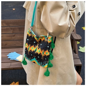 Détail d'un sac cabas brodé ethnique avec pompons verts dans un cadre automnal extérieur