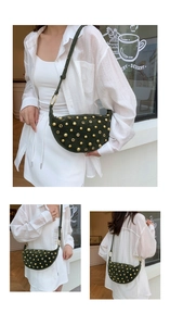 Detail of dark green crescent moon bag with gold punk studs and eyelet decorations