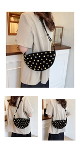 Detail of black leather crescent bag with golden studs and metal grommets punk style