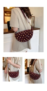 Detail view of burgundy suede crescent bag with gold rivets and metallic eyelet decor