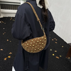Detail of vintage brown suede crescent bag with metal rivets worn by a model