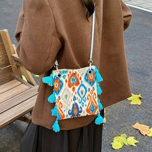 Sac à bandoulière ethnique avec pompons et motifs géométriques porté par un modèle