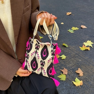 Sac fourre-tout ethnique à motifs géométriques et pompons roses porté par un mannequin