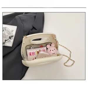 Detail showing internal capacity of the cream acrylic clutch bag with golden chain