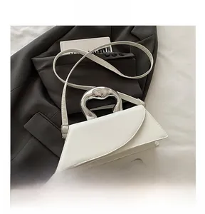 Detail of white geometric PU leather handbag with silver metallic curved handle