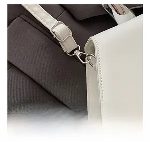 Detailed macro view of bright silver metal hardware and white synthetic leather on a bag