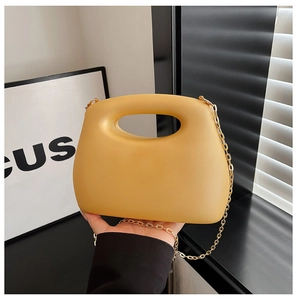 Detail of yellow acrylic evening box bag with smooth matte finish and gold chain strap