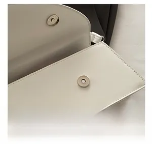 Close-up of the silver magnetic snap closure on a white lychee grain leather handbag