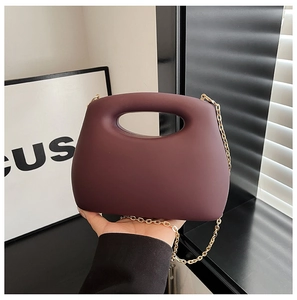 Detail of burgundy acrylic clutch featuring a matte finish and gold metal chain strap