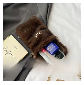 Internal capacity of brown plush crossbody bag showing phone and lipstick storage