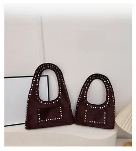Detail view of brown suede shoulder bags featuring silver stud accents and soft texture