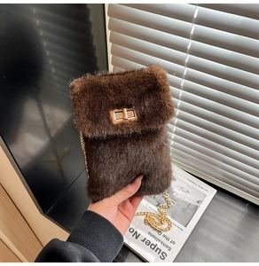 Detail of plush brown faux fur crossbody bag featuring golden chain and metallic twist lock