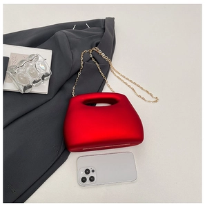 Top view of red acrylic mini evening bag with gold chain strap on grey suit background