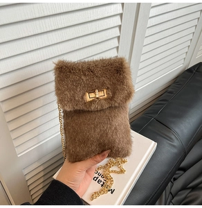 Detail of plush brown crossbody bag featuring golden twist lock and chain strap
