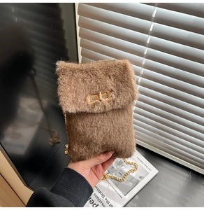Close-up of brown plush phone bag featuring golden twist lock and metal chain strap