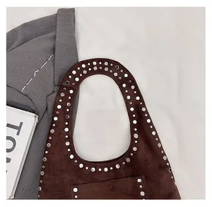 Close-up of silver studs on dark brown suede handbag with detailed metallic rivet accents
