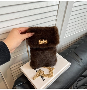 Detail of plush faux fur crossbody bag with golden chain strap and metal swivel lock