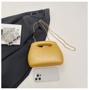 Detail view of mustard yellow acrylic box bag with golden chain and cutout handle