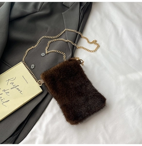 Detail of dark brown faux fur phone bag with shimmering texture and golden metal chain