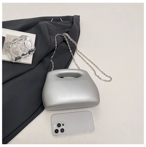 Silver semi-circular acrylic evening bag with top handle and metal chain on grey background