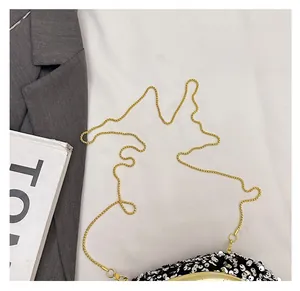 Détail de la pochette de soirée à paillettes noires avec cadre doré et chaîne