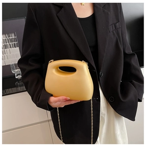 Close-up of bright yellow acrylic box bag with gold chain strap and oval handle