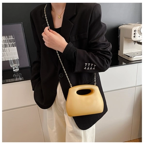 Detail of yellow acrylic crossbody bag with hollow handle and gold chain strap on model