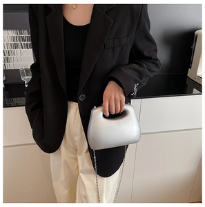 Detail of silver matte acrylic clutch bag with hollow handle and metal chain strap